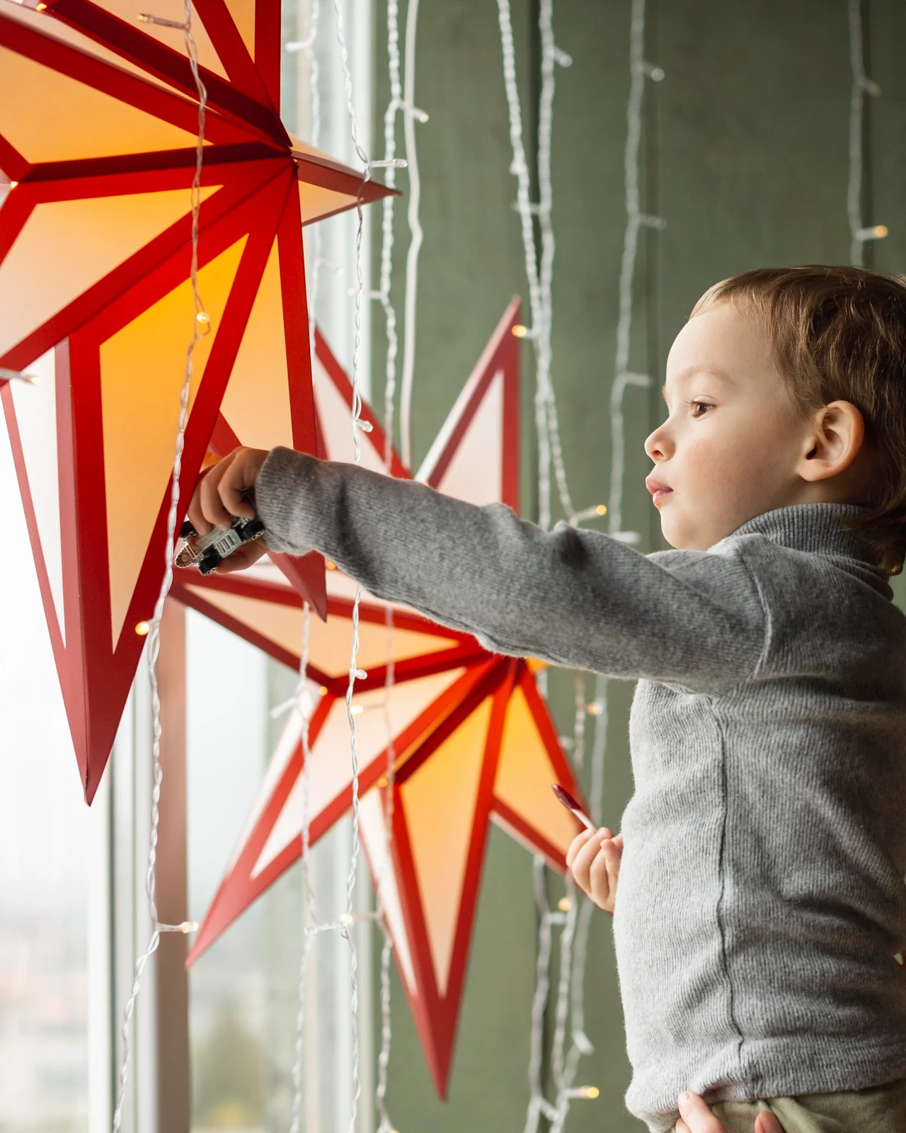 Young child reaching towards glowing star decorations at home
