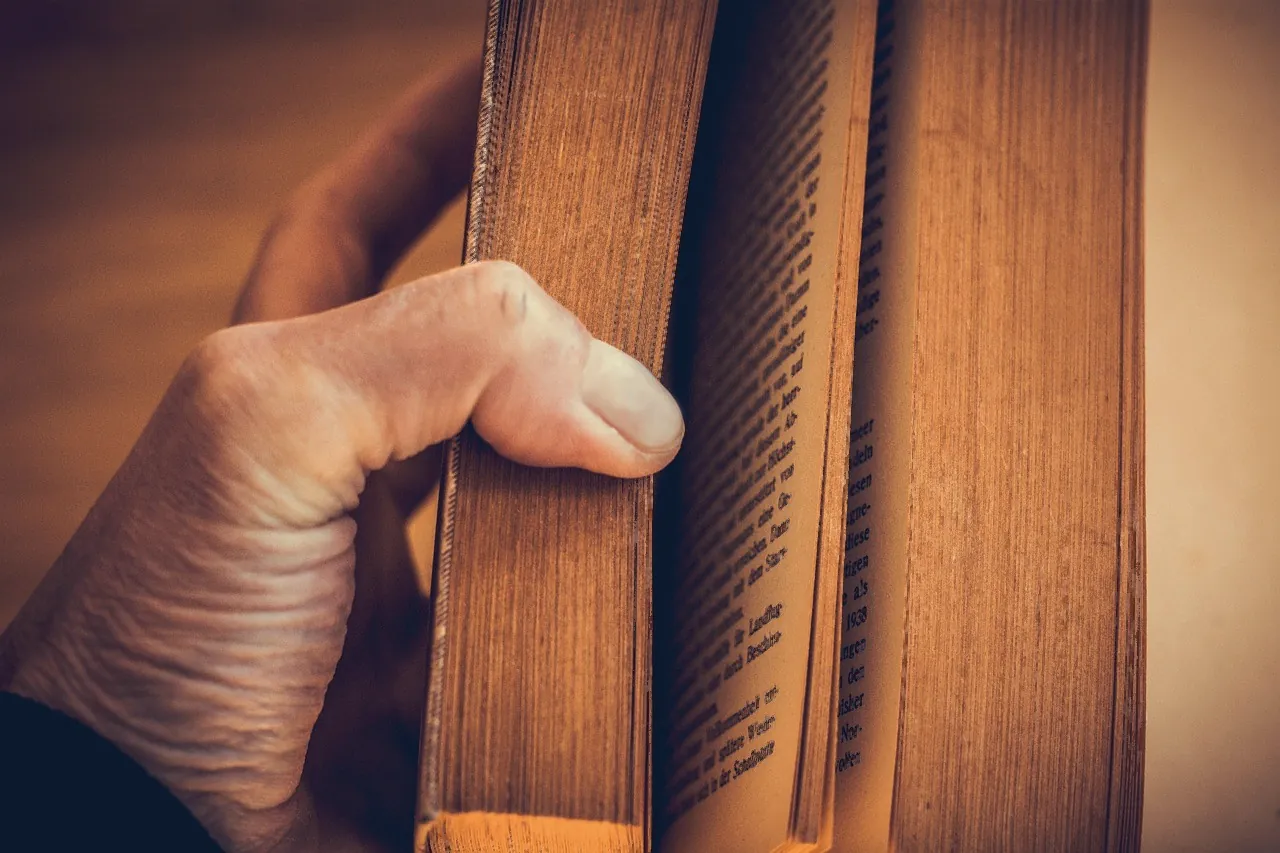Hand turning the pages of a well-read book